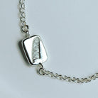 silver feather bracelet on a white dish