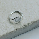 Silver ring with a sunrise design on a stone surface