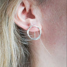 Close-up of a silver hoop earring worn by a person with blonde hair.